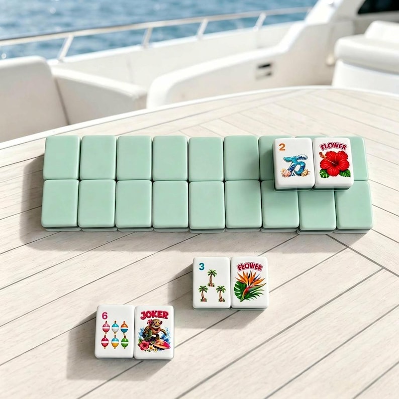 Pode incluir: Um conjunto de pe&ccedil;as retangulares de mahjong com verso verde-claro e frente branca. Algumas pe&ccedil;as apresentam ilustra&ccedil;&otilde;es coloridas de um hibisco vermelho, uma onda azul, palmeiras, uma flor ave-do-para&iacute;so, boias de pesca e uma tartaruga surfista.