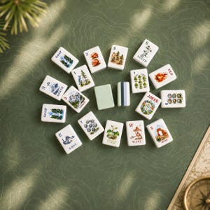 May include: A collection of rectangular mahjong tiles featuring colorful illustrations of national parks, landscapes, and nature scenes. The tiles include text labels such as North, South, East, West, Soap, Red, Joker, and various numbered designs.