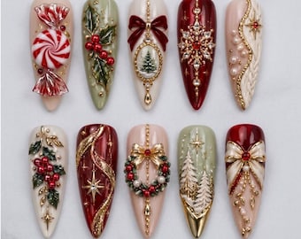May include: Ten almond-shaped press-on nails featuring intricate Christmas designs. Decorations include a red and white peppermint candy, holly berries, gold bows, a miniature tree, snowflakes, pearls, wreaths, and pine trees in red, green, and gold.