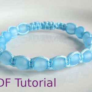 Close up of light blue beaded macrame square knot bracelet with slider closure. With PDF Tutorial written on the image.