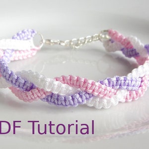 A bracelet that has a 3 braid effect. Each braid is made using square knots and each braid is in a separate colour - white, lilac and pink. With a metal chain and clasp closure. With PDF Tutorial written on the image.