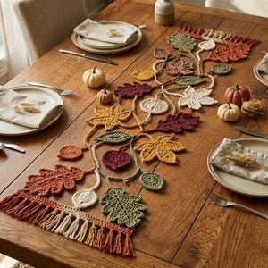 May include: A crochet table runner featuring a vine pattern with various autumn-colored leaves in shades of orange, yellow, green, and burgundy. The runner includes intricate leaf shapes and is finished with a fringed edge at both ends.