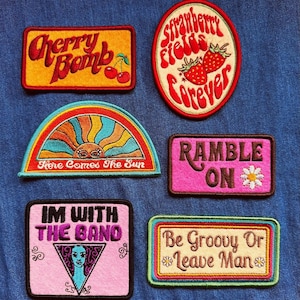 May include: A selection of embroidered patches with vintage-inspired designs and text. The patches display phrases such as "Cherry Bomb," "Strawberry Fields Forever," "Here Comes The Sun," "Ramble On," "I'm With The Band," and "Be Groovy Or Leave Man."