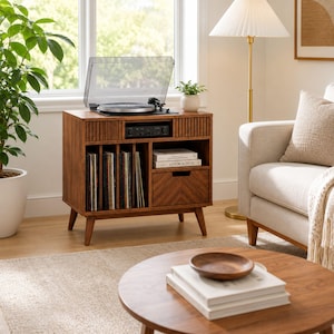 Può includere: Un mobile giradischi in legno con un piatto sulla parte superiore, un pannello frontale a listelli, uno scomparto centrale per apparecchiature audio, fessure verticali per dischi in vinile e un cassetto con motivo a spina di pesce su quattro gambe affusolate.