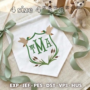 May include: A white fabric banner featuring an embroidered green crest with the letters TMA, two ducks, and cattails. The banner has sage green ribbon ties at the top corners. Text indicates 4 size 4", 5", 6", 7" and file formats EXP, JEF, PES, DST, VP3, HUS.