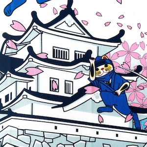 May include: A white fabric print featuring a black and white Japanese castle with multiple tiers and dark roof accents. A blue ninja cat is positioned on the roof, surrounded by falling pink cherry blossom petals against a white background.
