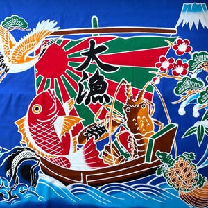 May include: A vibrant blue fabric banner featuring a traditional Japanese fishing boat design. The scene includes a red sun, a large red fish, a brown lobster, a flying crane, a turtle, pine trees, and Mount Fuji, with the black kanji characters 大漁.