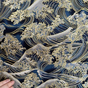 May include: A blue and gold fabric with a repeating pattern of stylized waves. The waves are outlined in gold and have a textured appearance.