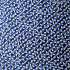 May include: Close-up of a fabric with a repeating pattern of white oval shapes and small pink and brown accents on a navy blue background. The pattern is arranged in diagonal rows, separated by light blue stripes.