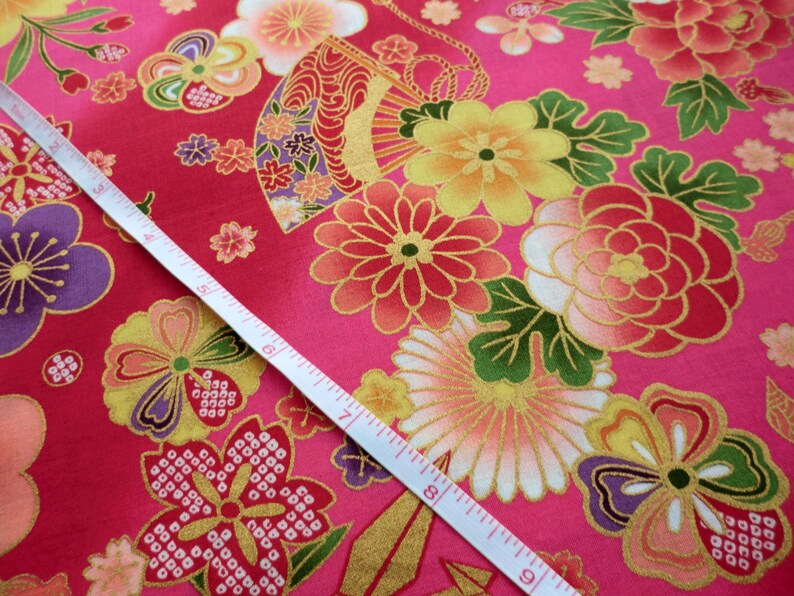 Pu&ograve; includere: Tessuto rosa con un motivo floreale dorato e rosso. Il tessuto presenta una variet&agrave; di fiori, tra cui crisantemi, peonie e fiori di ciliegio. Il tessuto &egrave; impreziosito da filo dorato e ha una leggera lucentezza.