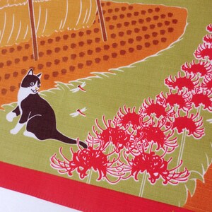May include: A black and white cat with green eyes sits on a green background with red spider lily flowers and dragonflies. The background is a field of orange and brown.