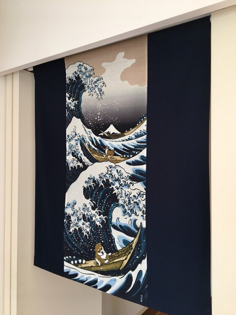 May include: A blue and white tapestry featuring a large wave with a small boat and two dogs. The tapestry is hanging on a white wall.