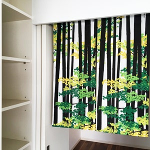 May include: A white, black, green, and yellow patterned curtain with a forest scene. The curtain is hanging in a doorway.