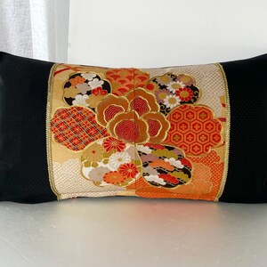 Pode incluir: Travesseiro preto com um padr&atilde;o floral colorido em tons de laranja, vermelho, dourado e branco. O padr&atilde;o floral &eacute; um design japon&ecirc;s tradicional.