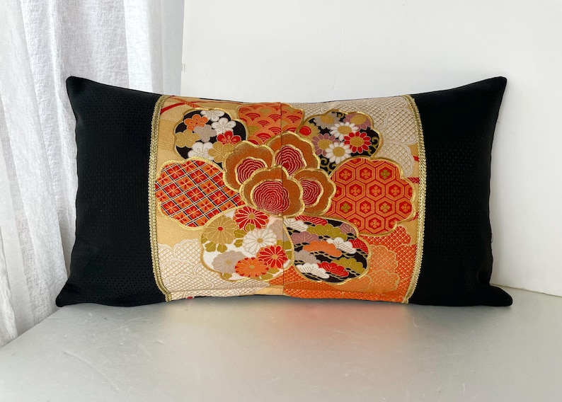Pode incluir: Travesseiro preto com um padr&atilde;o floral colorido em tons de laranja, vermelho, dourado e branco. O padr&atilde;o floral &eacute; um design japon&ecirc;s tradicional.