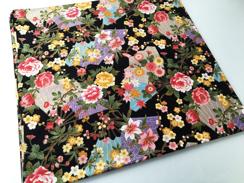 Puede incluir: Tela negra con un patr&oacute;n floral que presenta flores rosas, amarillas y blancas, detalles dorados y un dise&ntilde;o geom&eacute;trico.