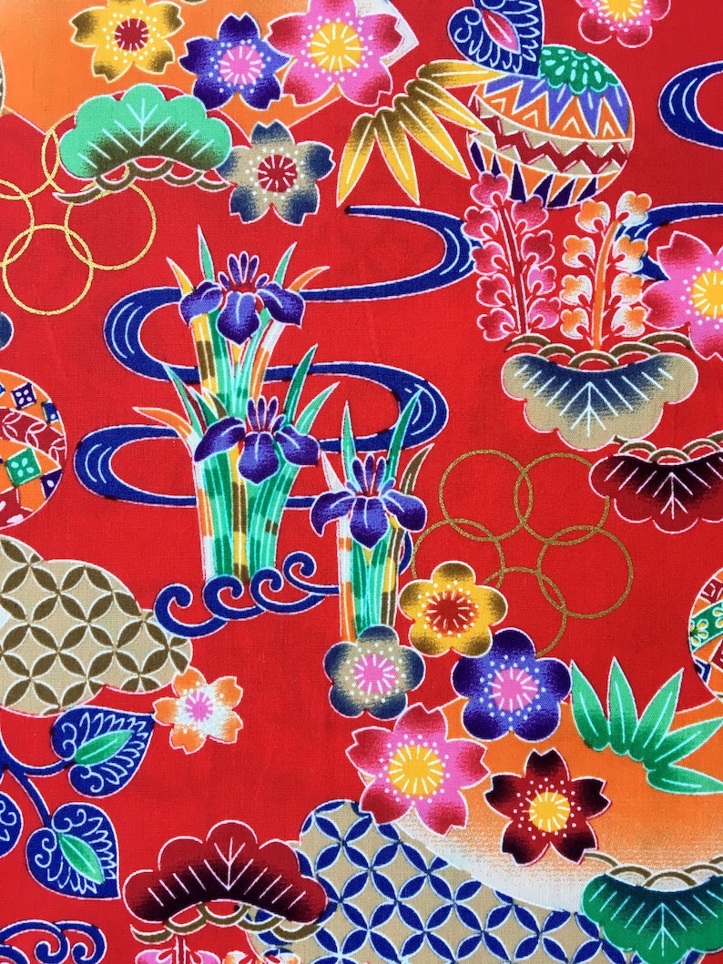 May include: Red fabric with a colorful Japanese-inspired pattern. The pattern features flowers, leaves, and geometric shapes. The fabric is perfect for quilting, sewing, or crafting.