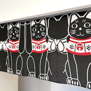 Puede incluir: Cortina Maneki-neko en blanco y negro con un patr&oacute;n repetido. Cada gato tiene un collar rojo con una campana y levanta una pata. La cortina cuelga de una gu&iacute;a plateada.