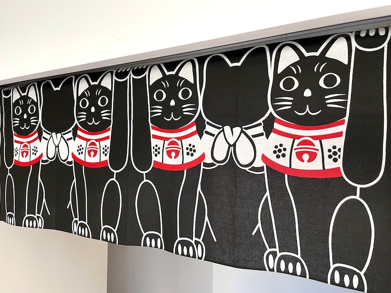 Puede incluir: Cortina Maneki-neko en blanco y negro con un patr&oacute;n repetido. Cada gato tiene un collar rojo con una campana y levanta una pata. La cortina cuelga de una gu&iacute;a plateada.