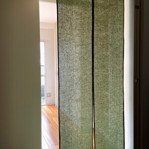 Puede incluir: Dos separadores de ambiente de lino verde oscuro cuelgan de una v&iacute;a en una puerta. Los separadores est&aacute;n hechos de una tela texturizada y tienen un ribete negro.