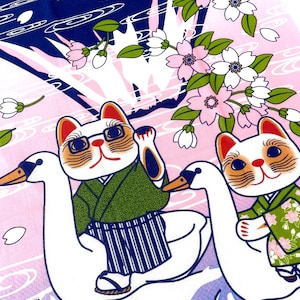 May include: A fabric print featuring two white cats wearing green kimonos, each riding a white swan. The cats are surrounded by pink cherry blossoms and white petals against a background of dark blue and light pink water ripples.