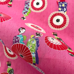 May include: Pink fabric with a repeating pattern of geishas and red and white umbrellas. The geishas are wearing traditional Japanese clothing and carrying umbrellas.