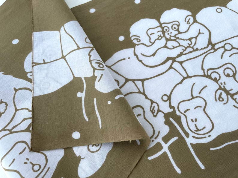 May include: Olive green and white fabric featuring a repeating pattern of cartoon monkeys. The monkeys are depicted in a playful, stylized manner, with white outlines against the olive background. The fabric is folded, showing both sides.