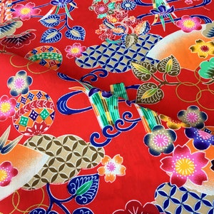 May include: Red fabric with a repeating pattern of colorful flowers, geometric shapes, and stylized bamboo. The fabric has a traditional Japanese design.