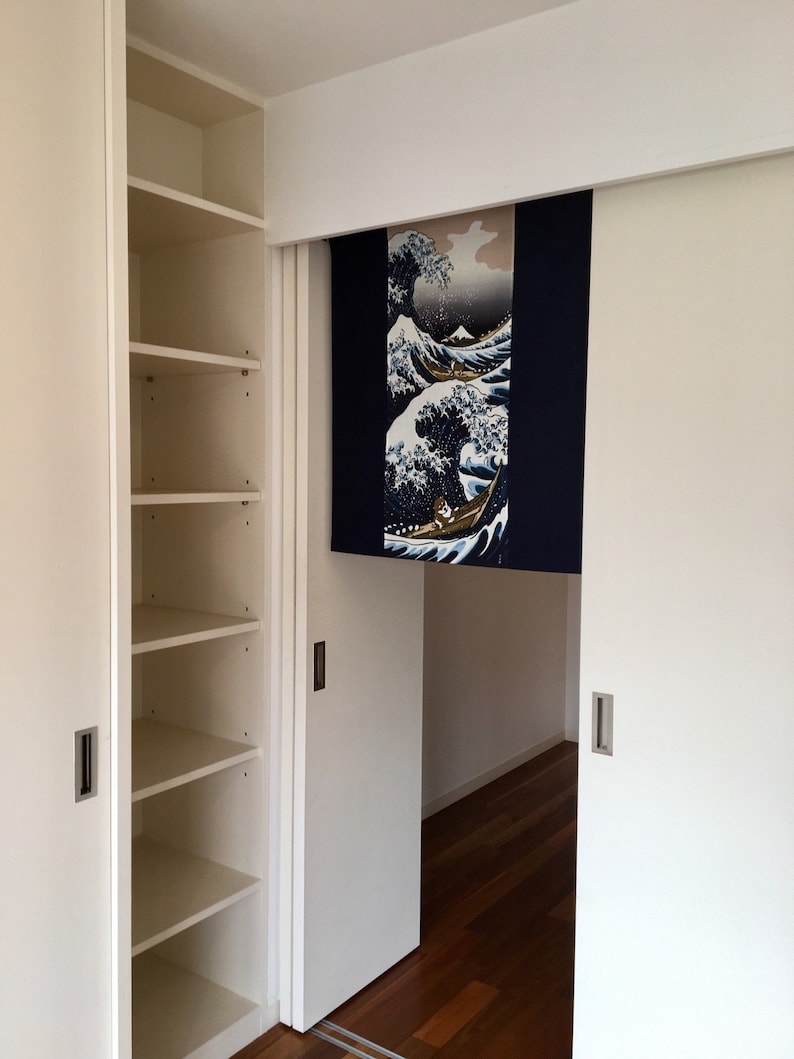 May include: White closet with sliding doors and shelves. The sliding doors are open to reveal a room with a wooden floor. A Japanese-style room divider with a blue and white wave design hangs on the door.