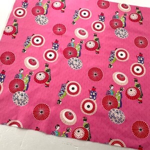 May include: Pink fabric with a repeating pattern of geishas and umbrellas. The geishas are wearing colorful kimonos and holding parasols. The umbrellas are red, white, and black.