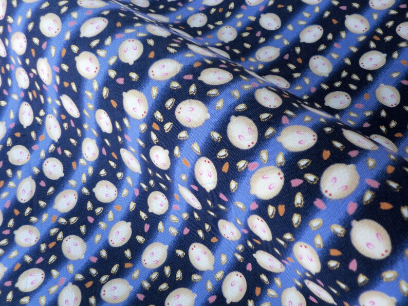 May include: Close-up of a fabric with a repeating pattern of white, oval-shaped designs with pink accents, scattered across a dark blue background with blue stripes. Small orange and pink shapes are also present.