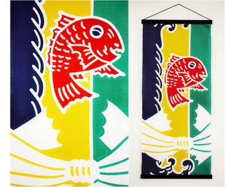 Può includere: Un rotolo appeso giapponese tradizionale con un disegno di pesce rosso su sfondo giallo, verde e blu. Il rotolo è montato su un'asta di legno nera.