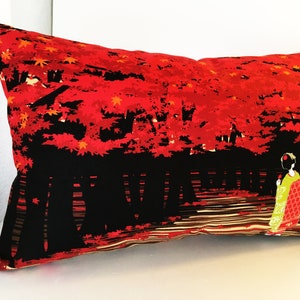 May include: Red and black pillow with a Japanese-inspired design featuring a woman in a kimono walking through a forest of red maple trees.