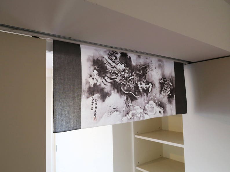 Puede incluir: Panel decorativo de tela con una ilustraci&oacute;n de drag&oacute;n en blanco y negro. Montado sobre una puerta, con una secci&oacute;n de tela negra s&oacute;lida a la izquierda. Se pueden ver caracteres japoneses en el lado derecho.
