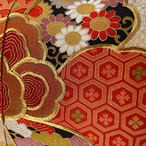 Pode incluir: Uma almofada vermelha, dourada e preta com um design floral. A almofada &eacute; feita de um tecido luxuoso com bordados intrincados.
