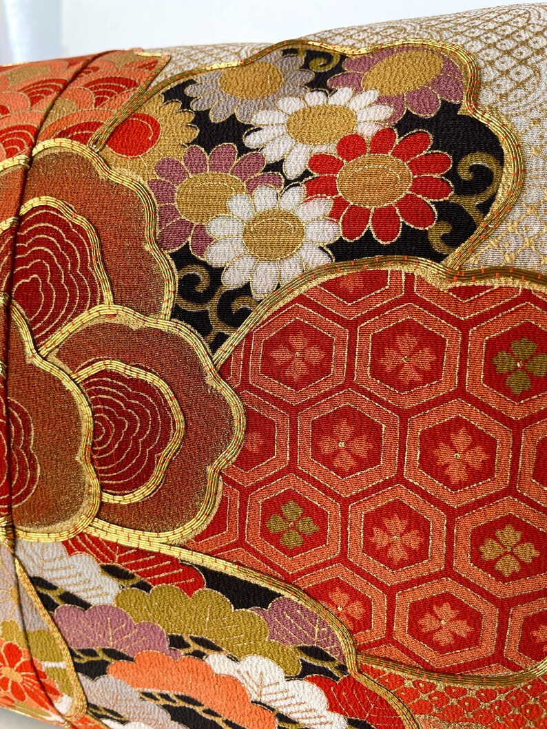 Pode incluir: Uma almofada vermelha, dourada e preta com um design floral. A almofada &eacute; feita de um tecido luxuoso com bordados intrincados.