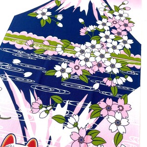 May include: A fabric textile featuring a graphic print of Mount Fuji in dark blue with a white snow-capped peak, surrounded by pink and white cherry blossoms, green leaves, and stylized water waves, with a cat wearing glasses at the bottom.