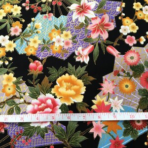 Puede incluir: Tela negra con un patr&oacute;n floral dorado y morado. La tela presenta una variedad de flores, incluyendo lirios, peon&iacute;as y crisantemos. La tela est&aacute; acentuada con formas geom&eacute;tricas doradas y moradas. La tela se mide con una cinta m&eacute;trica blanca.