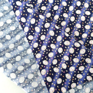 May include: Two fabric swatches with a repeating pattern of white lemon-like shapes on a navy blue background. One swatch is a lighter blue with the same pattern. The fabric has a diagonal striped design.
