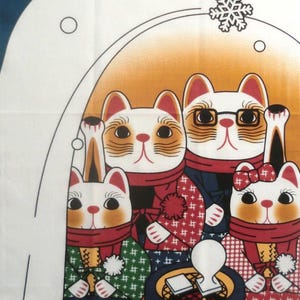 May include: A rectangular fabric panel featuring a winter scene with four cats wearing scarves and patterned clothing gathered around a small dark green brazier. A small white creature sits in an igloo below, with white snowflakes on a blue background.