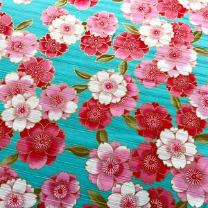 May include: A turquoise fabric with a repeating pattern of pink and red flowers with gold accents.