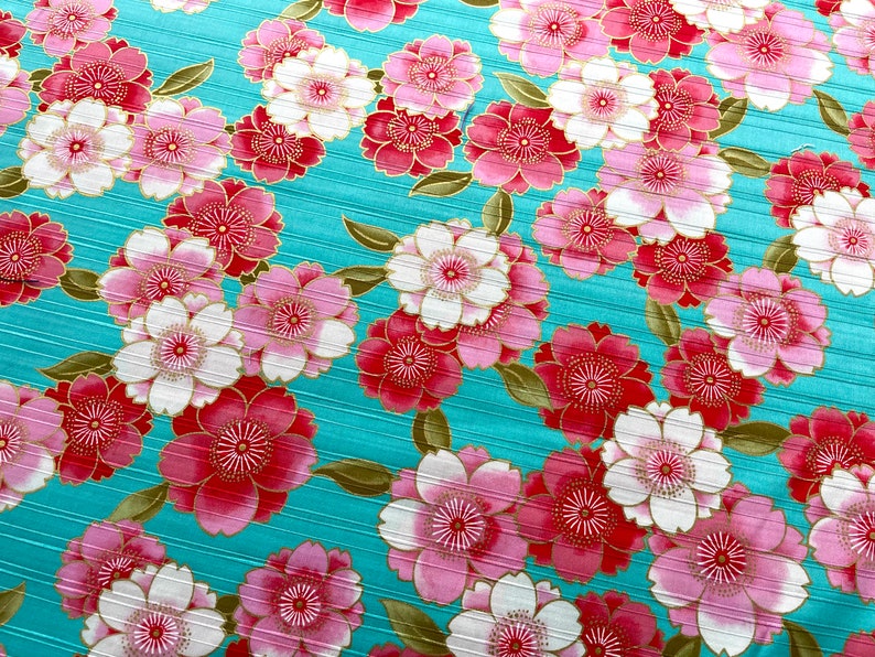 May include: A turquoise fabric with a repeating pattern of pink and red flowers with gold accents.