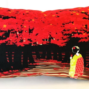 May include: A red and black throw pillow with a Japanese-inspired design. The pillow features a woman in a traditional kimono standing in a forest of red maple trees.