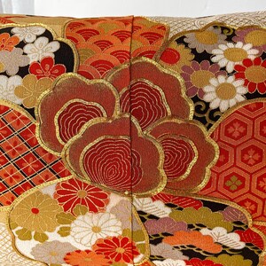 Pode incluir: Uma almofada retangular com um padr&atilde;o de inspira&ccedil;&atilde;o japonesa em vermelho, dourado e branco. A almofada &eacute; feita de um tecido macio e luxuoso e apresenta uma variedade de desenhos intrincados, incluindo flores, nuvens e formas geom&eacute;tricas.