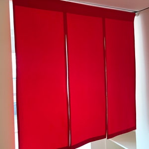 May include: Three red fabric panels with a dark red border hang from a track. The panels are closed, blocking the view behind them.