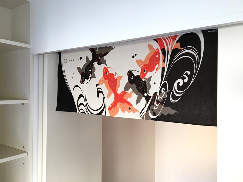 May include: A black and white fabric panel with a design of orange and black fish swimming in a stylized wave pattern. The fabric is hanging from a white ceiling.