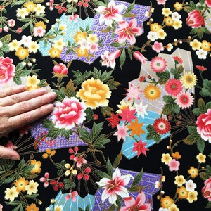 Puede incluir: Tela negra con un patr&oacute;n floral con flores rosas, amarillas y blancas. La tela tiene un brillo met&aacute;lico dorado y un dise&ntilde;o de inspiraci&oacute;n japonesa.