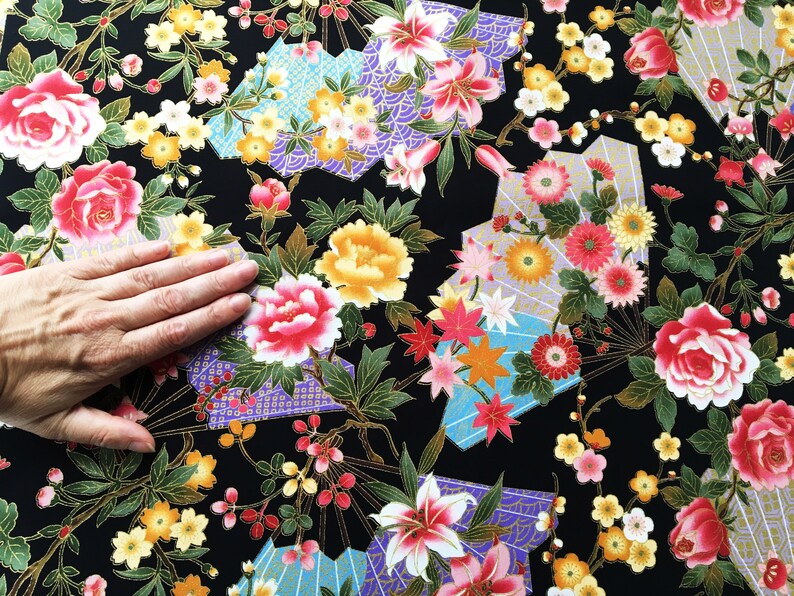 Puede incluir: Tela negra con un patr&oacute;n floral con flores rosas, amarillas y blancas. La tela tiene un brillo met&aacute;lico dorado y un dise&ntilde;o de inspiraci&oacute;n japonesa.