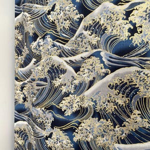 May include: A navy blue fabric with a repeating pattern of gold and white waves. The waves are stylized and resemble the Great Wave off Kanagawa.