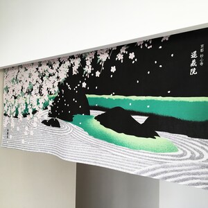 May include: A black and green Japanese-style room divider with a white and pink cherry blossom tree design. The divider has a white and grey sand garden design at the bottom. The text on the divider reads "遠山に桜".